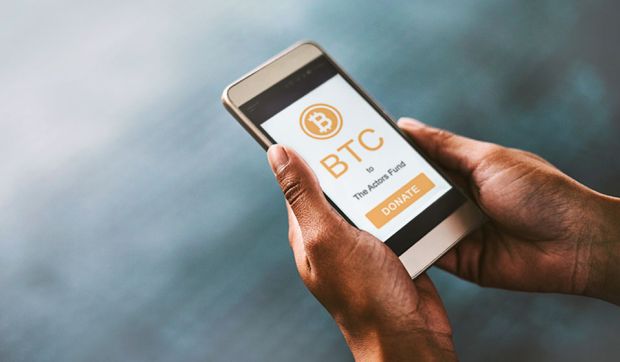 Hands holding a smartphone with Bitcoin logo on the screen