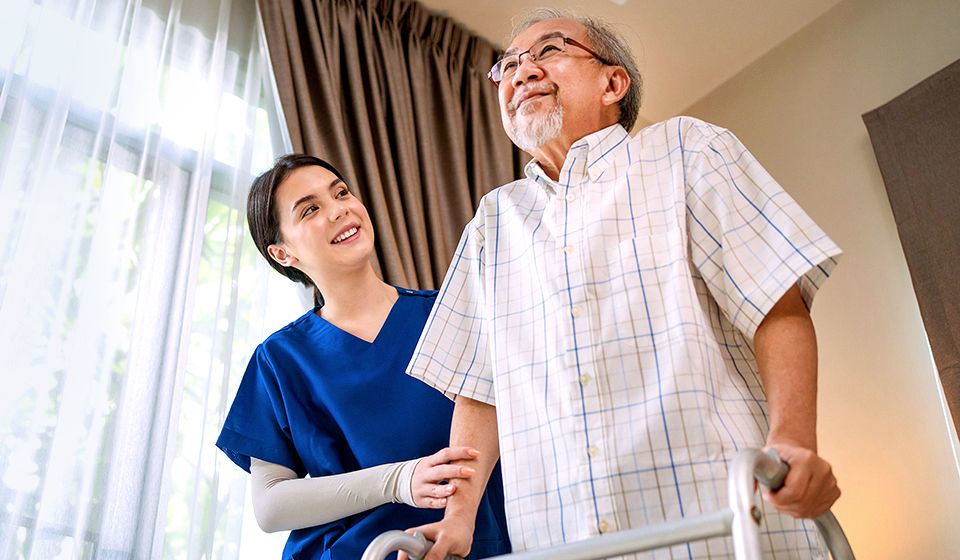 A man using a walker to stand up while his caregiver holds his arm for support