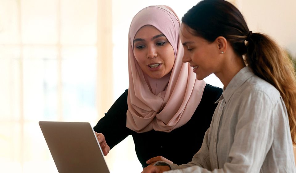 Two women looking at a computer together.