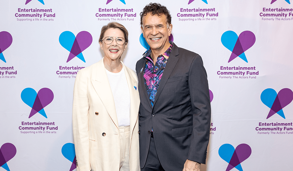 Annette Bening and Brian Stokes Mitchell standing in front of a backdrop with the Entertainment Community Fund Logo