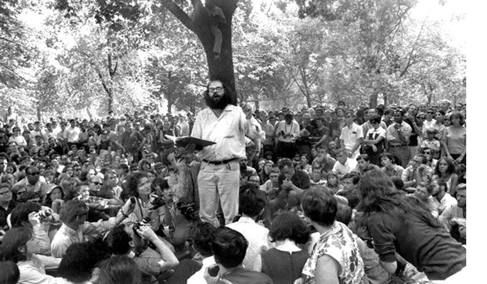 A man stands outside in front of a tree reading to a crowd surrounding him.