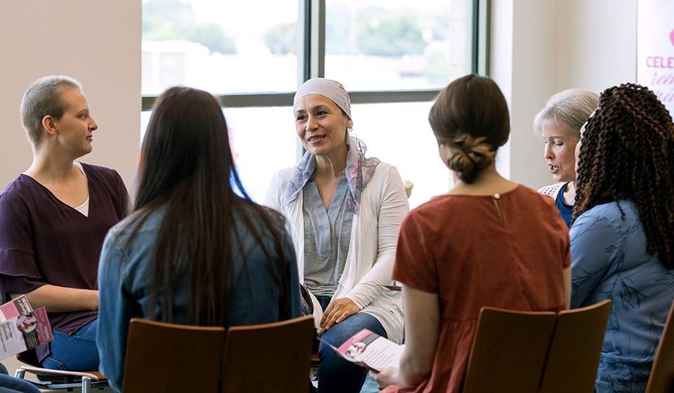 A women's support group sits in a circle listening to a member speak.